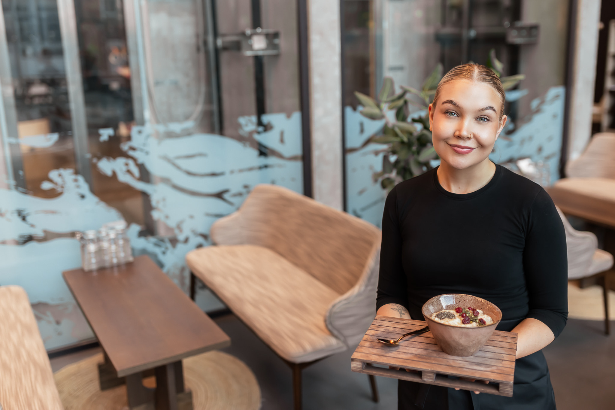 Hymyilevä tarjoilija pitelee puuroannosta tarjottimella.